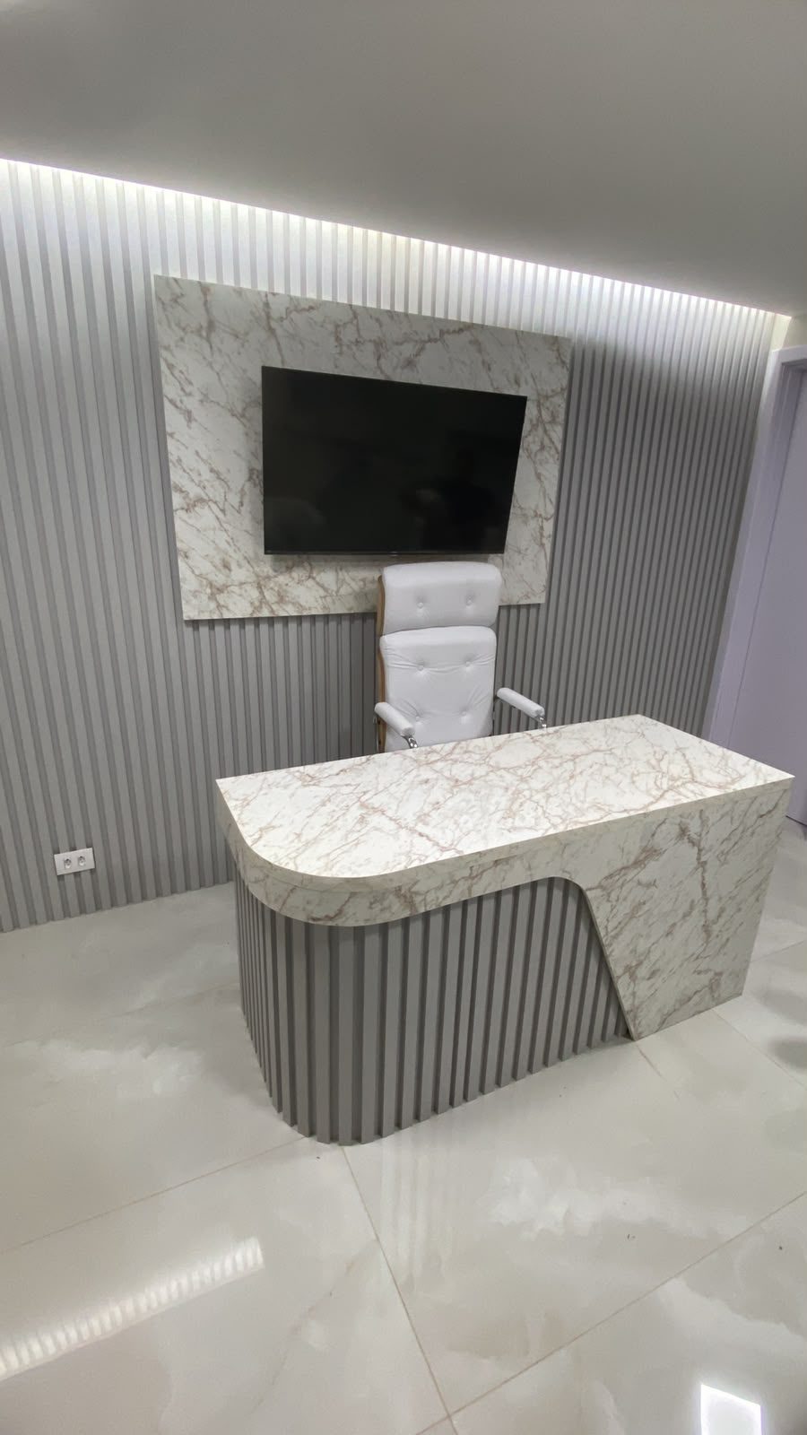 Consultório com mesa marmorizada e ripado com iluminação, foto 1 de 5