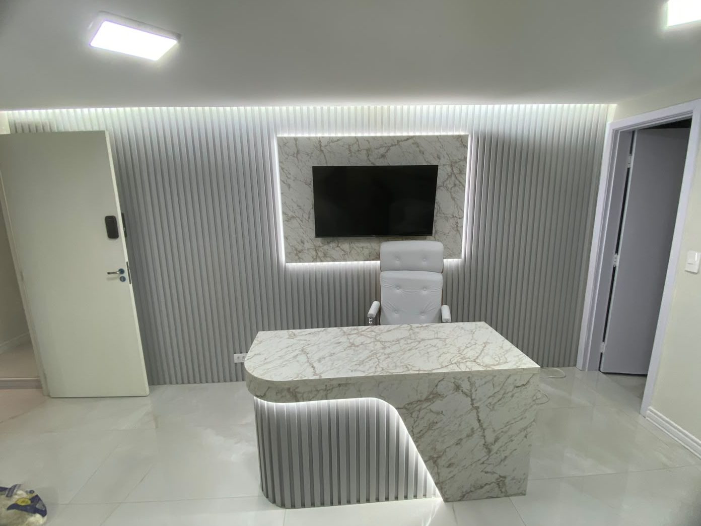 Consultório com mesa marmorizada e ripado com iluminação, foto 2 de 5