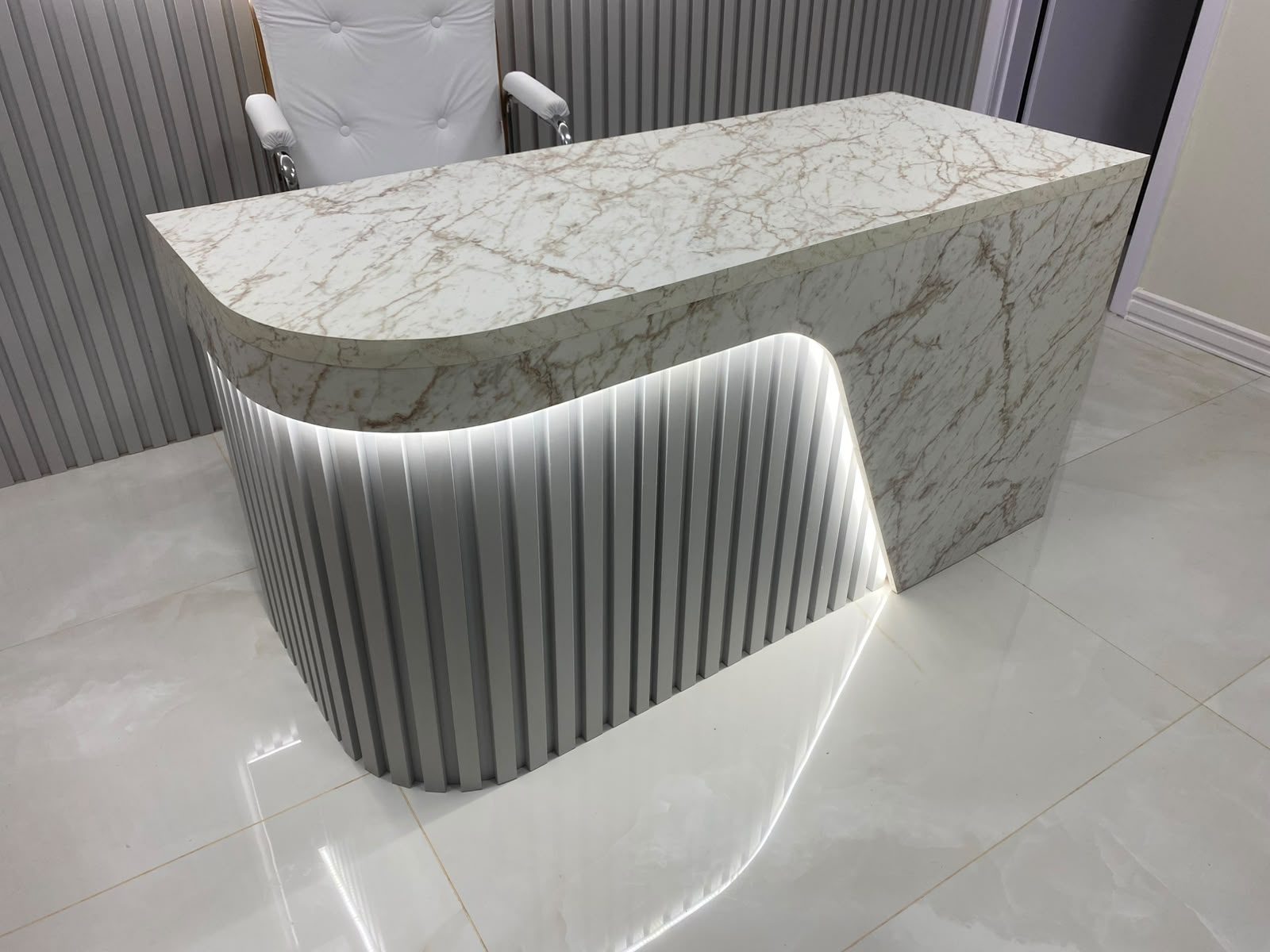 Consultório com mesa marmorizada e ripado com iluminação, foto 3 de 5