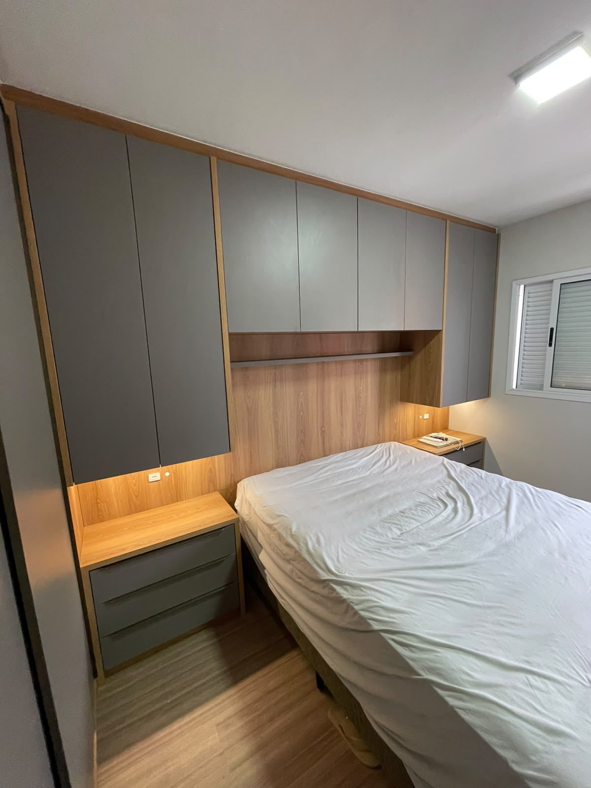 Quarto com guarda-roupa cinza e cabeceira com iluminação, foto 2 de 2